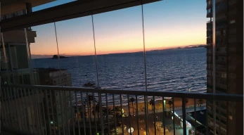 Vistas al mar y atardecer a través de cortinas de cristal en terraza